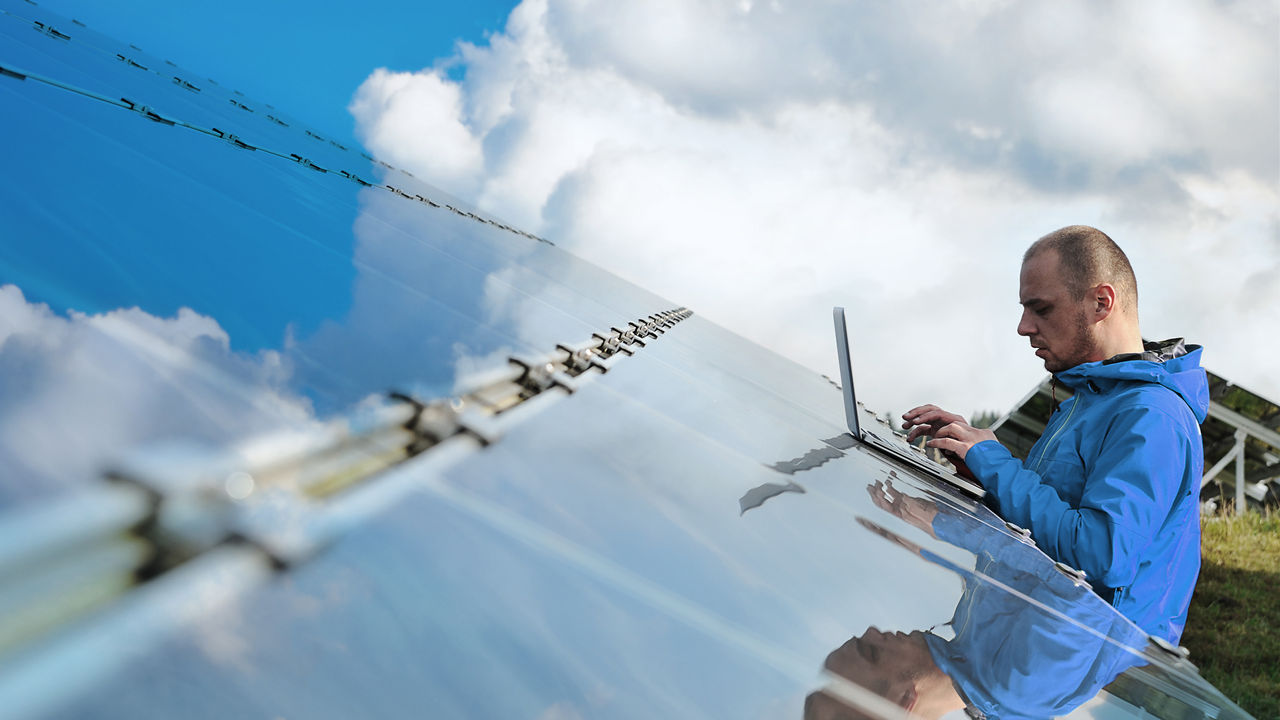 Male engineer with laptop working on solar panels
