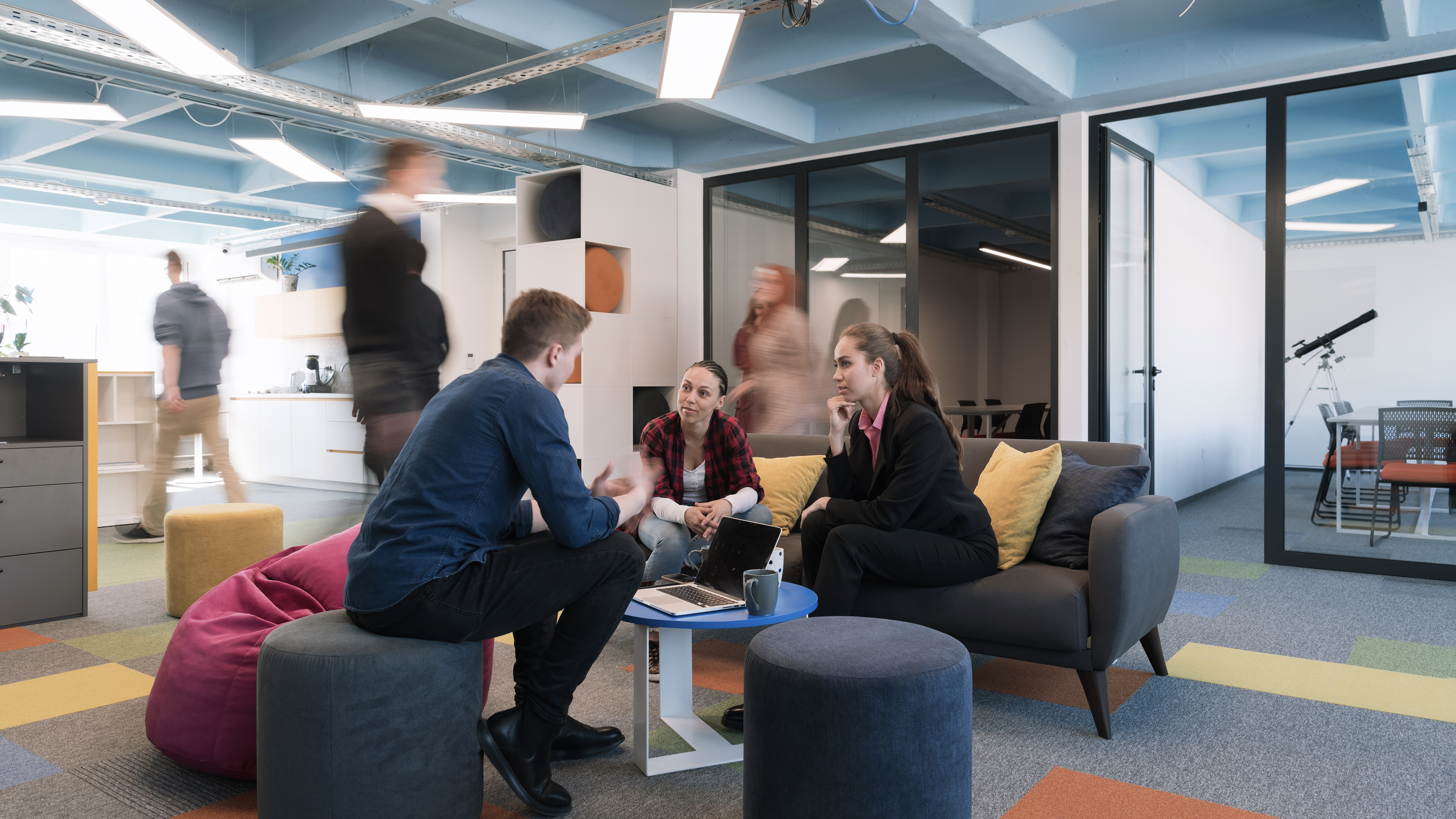 Multiethnic startup business team on meeting in a modern bright open space coworking office. Brainstorming, working on laptop. Group of coworkers walking around in motion blur. High quality photo