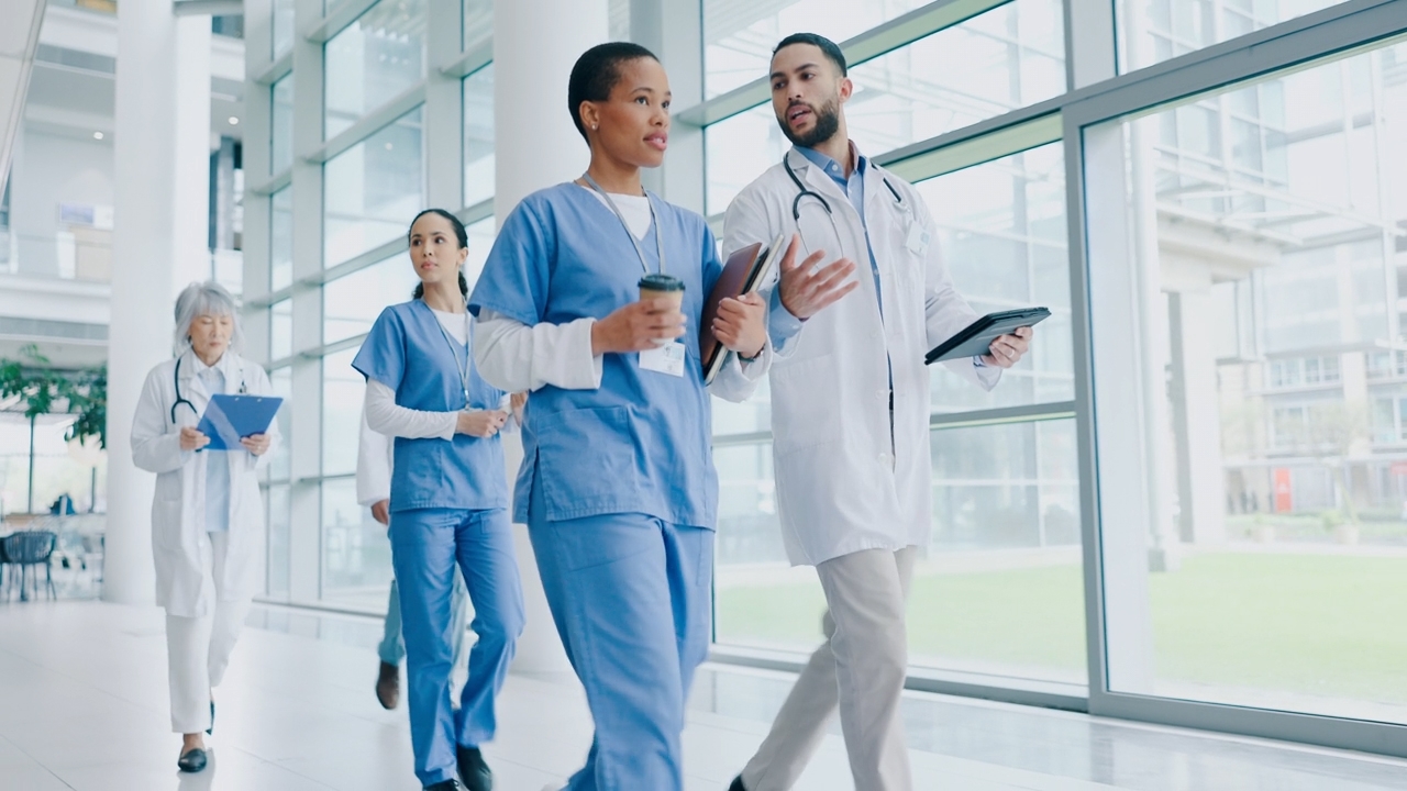 Group of healthcare professionals walking down a hall with windows
